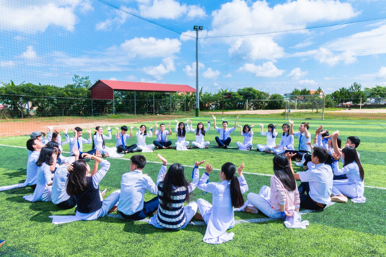 Mastering the First Impression: Your intriguing post title goes here Students seated in a circle on a school field engaging in outdoor activities.
